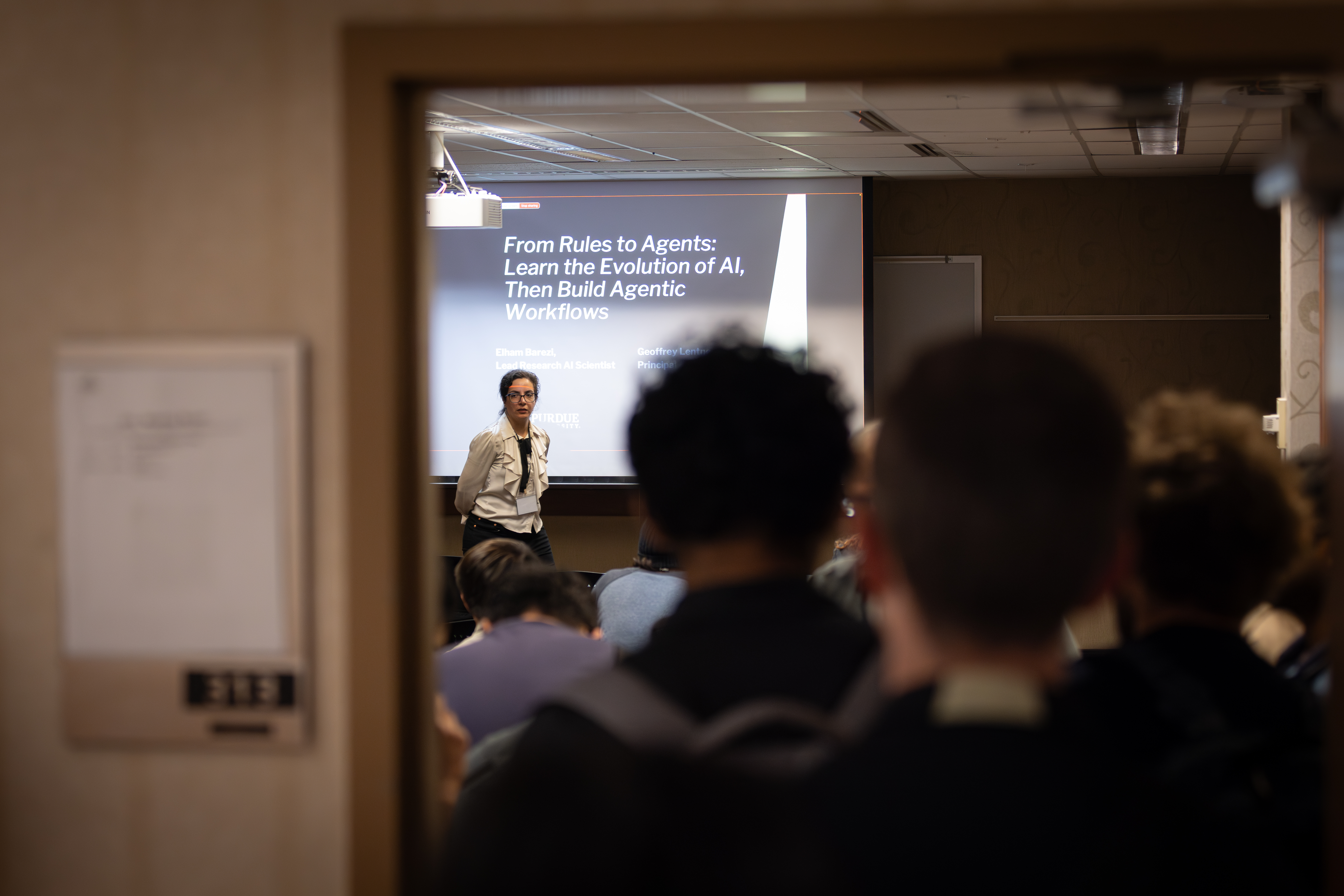 Elham Barezi in front of screen with line of attendees going out the door