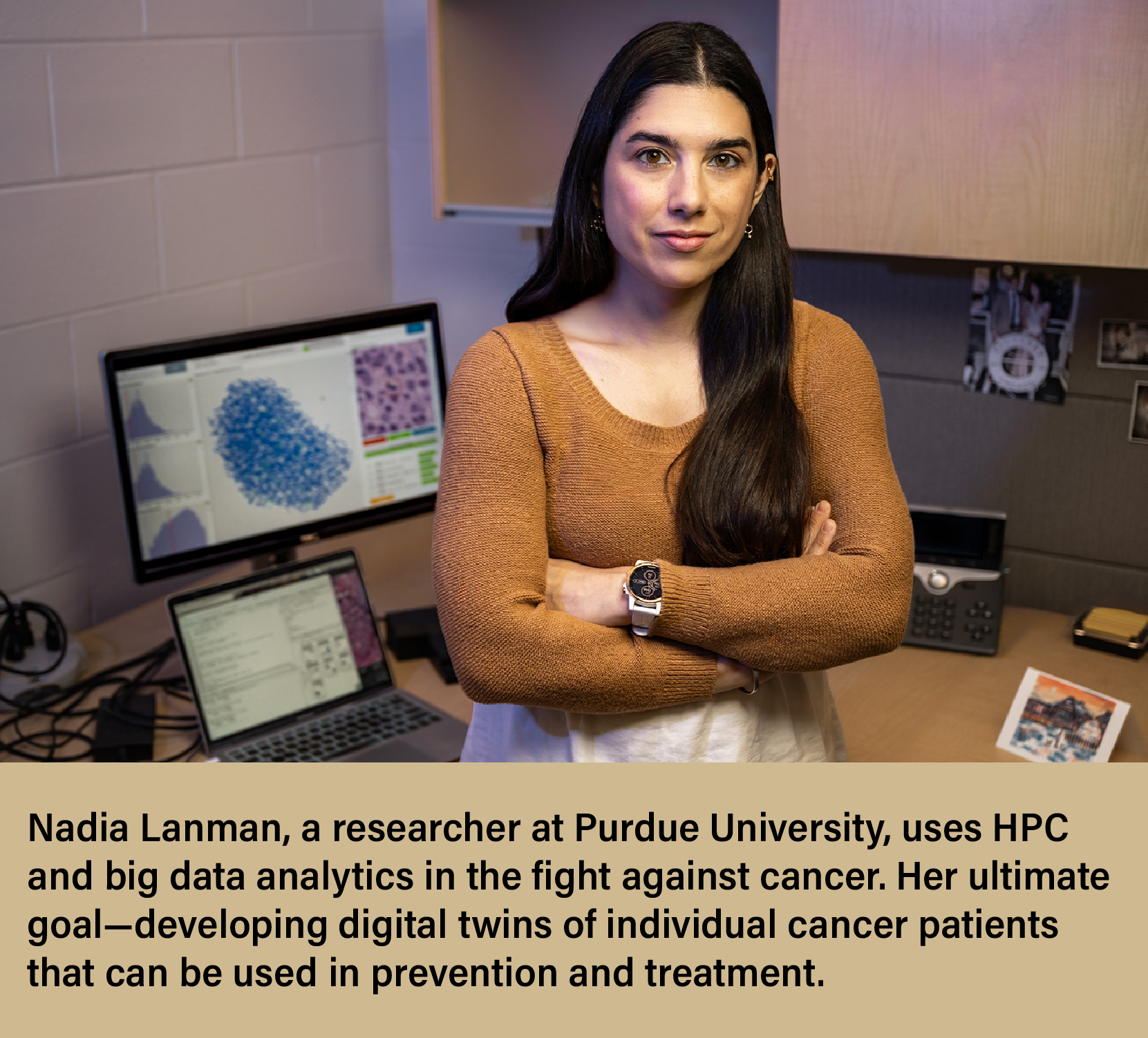Nadia Lanman standing in front of her workstation with cancer biology images on the screen in the background